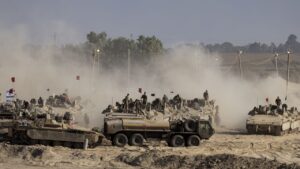 Israeli soldiers stand on armored personnel carriers and arrange military equipment near the Gaza border in southern Israel during the Gaza war.